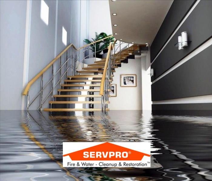 A room with stairs and water filled a few feet up and the SERVPRO logo at the bottom 