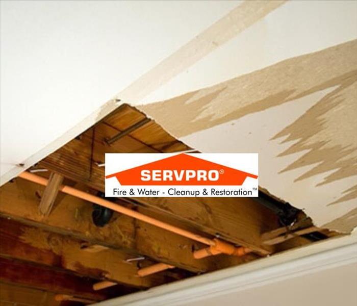 a ceiling that has been cut open in a square shape and the inside wood is exposed with the SERVPRO logo in the middle 