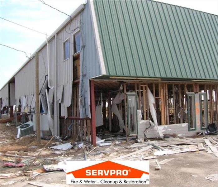 A house damaged by a storm with a big chunk of the bottom missing and the SERVPRO logo at the bottom