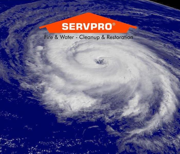 An aerial view of the earth with a bunch of clouds in circular motion creating a hurricane with the SERVPRO logo at the top  