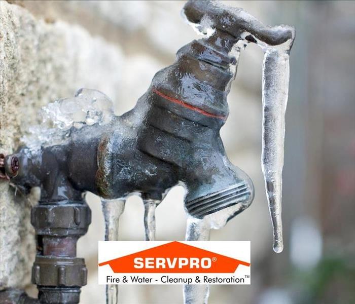 A close up photo of a small pipe that is frozen with ice on it and the SERVPRO logo at the bottom