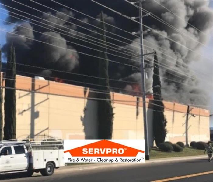 A building that has smoke coming out and trees around and the SERVPRO logo at the bottom