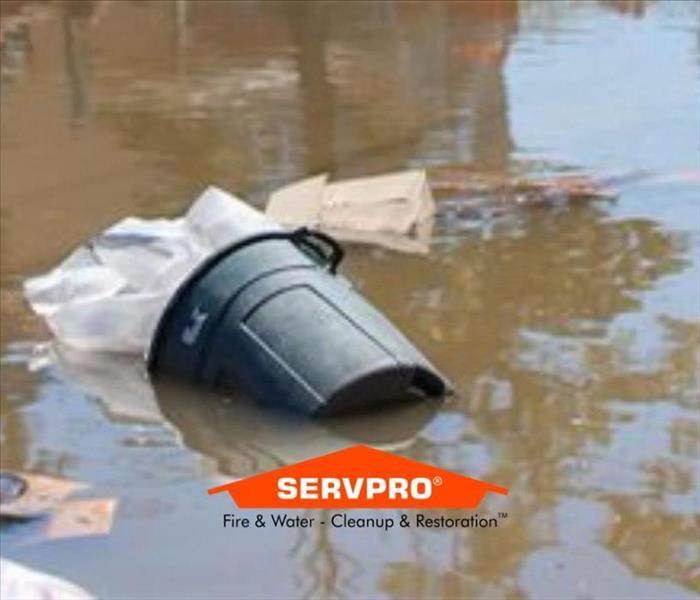 Flood waters with a black trash can floating and other trash with it