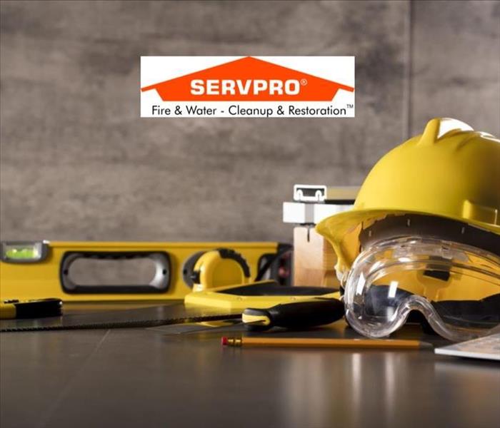 Yellow tools on a table in a grey room and the SERVPRO logo