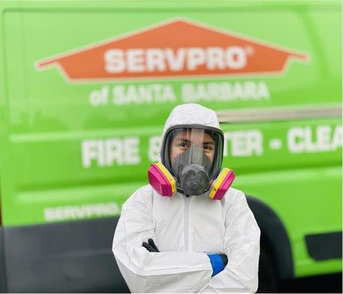 A SERVPRO employee in a white suit and a pink mask 